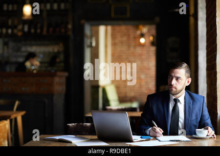 Businessman making notes in report Stock Photo