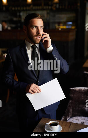 Worried businessman talking on phone in restaurant Stock Photo