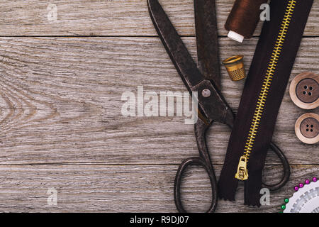 Old scissors and zipper for clothes with other tools on a wooden table with copy space Stock Photo