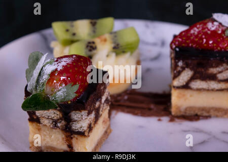 Tiny cupcake with kiwi, whipped cream and chocolate cake on a black marble table Stock Photo