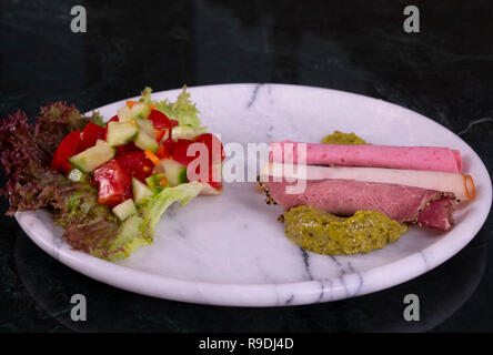 Meat plate with thinly sliced salami and jamon with salad on the marble background Stock Photo