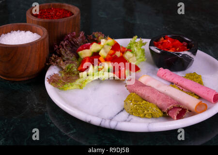 Meat plate with thinly sliced salami and jamon with salad on the marble background Stock Photo