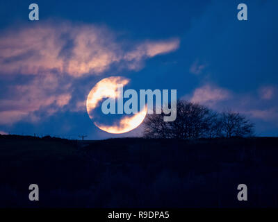 Wirksworth, UK. 22nd Dec, 2018. UK Weather: Winter Solstice Full Moon rising in between the clouds over Cromford Moor, Bolehill taken from the StarDisc above Wirksworth in the Derbyshire Dales Credit: Doug Blane/Alamy Live News