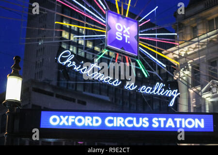 London, UK. 23rd Dec 2018. Christmas decorations and wet surface warnings at Oxford Circus. Shoppers with last minute purchases rush through the sales in the West End of London on the Sunday before Christmas, taking in the colourful decorations and captivating light displays in the capital. Credit: Imageplotter News and Sports/Alamy Live News Stock Photo