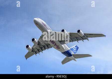 Airbus A380 passenger airliner shows its underside and flight control surfaces during a clean pass from right to left.