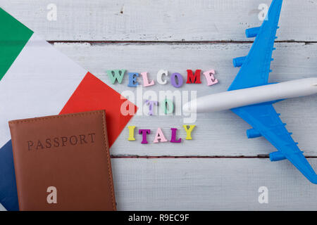 Travel time - colorful wooden letters with text 'Welcome to Italy' , flag of the Italy, airplane model, passport on white wooden background Stock Photo