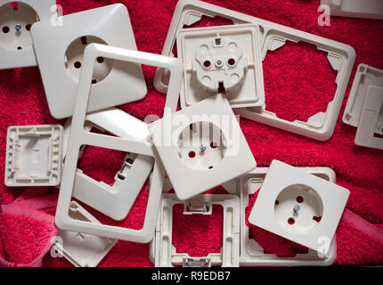 Group of old electrical outlet. White plastic electrical outlet after washing on the red texture background Stock Photo