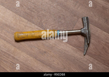 Blue with yellow metallic hammer on the laminate floor. Top view Stock Photo