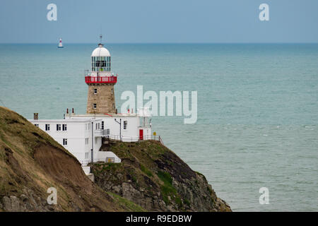 Baily Lighthouse, Dublin, Ireland - December 16 2018: View of The Baily Lighthouse on the Howth peninsula cliffs with a second illuminated lighthouse Stock Photo
