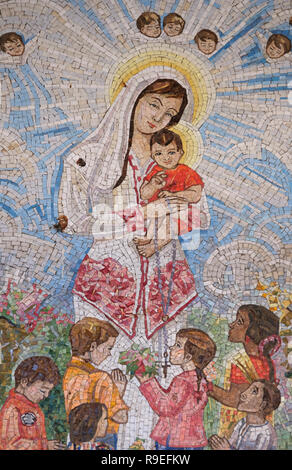 A mosaic painting depicting Mary and the infant Jesus donated by the Catholic community of Singapure in style that boldly reflect the culture of the country and visualize the annunciation in its own local eyes hanging on the wall around the front courtyard of the Roman Catholic Church of the Annunciation or the Basilica of the Annunciation in the city of Nazareth in Galilee northern Israel. Stock Photo