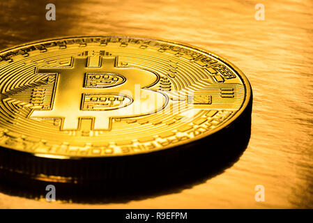 Golden bitcoin on a gold background. Physical e-cryptocurrency coins. Stock Photo