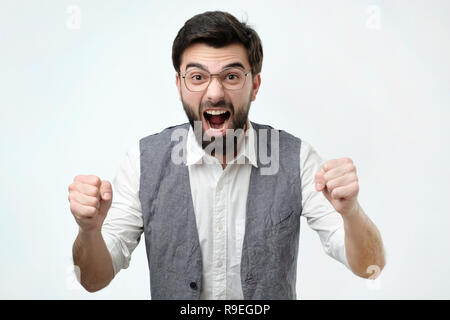 Mature hispanic man is happy with his win. He is holding his fists and shout Wow. Stock Photo