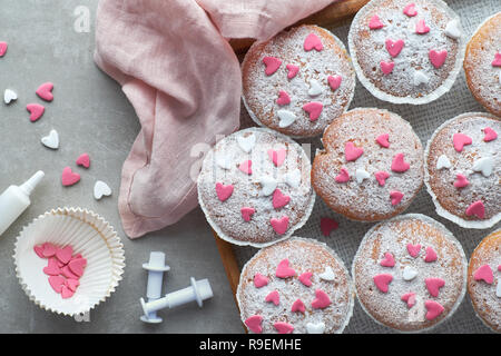 Sugar-sprinkled muffins with pink and white fondant icing hearts. Top view, birthday or Valentine concept. Stock Photo