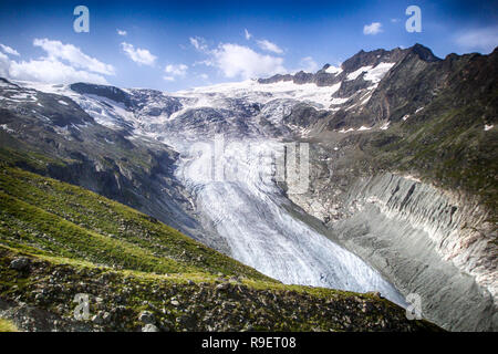 mountain landscape with green fields and snowy peaks and wild glacier in the Swiss Alps Stock Photo