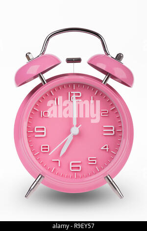 Pink alarm clock with the hands at 7 am or pm isolated on a white background. Stock Photo