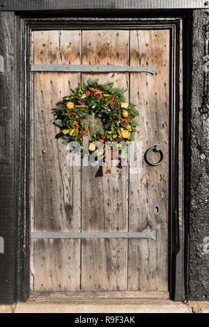 A traditional Christmas wreath on an Elizabethan (16C) oak entrance door and surround in Old Town, Stratford upon Avon, England, UK. Stock Photo