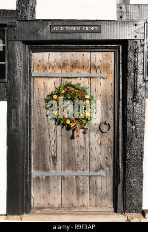A traditional Christmas wreath on an Elizabethan (16C) oak entrance door and surround in Old Town, Stratford upon Avon, England, UK. Stock Photo