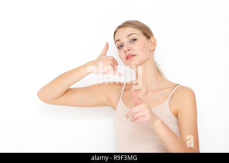 Portrait of happy young woman. Call me back please. Makes phone sign, indicates with index finger directly at camera, wants to speak with someone via  Stock Photo