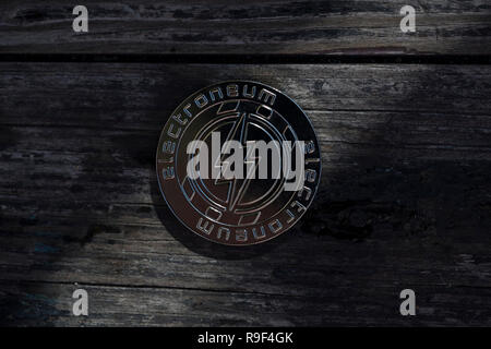 Electroneum cryptocurrency physical coin placed on the old wooden surface with the light shining through the gap Stock Photo