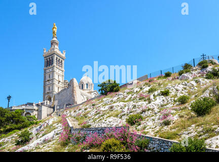 Low angle view of Notre-Dame de la Garde basilica on top of the hill in Marseille, France, seen from a secondary access trail with stairs in the rocks Stock Photo