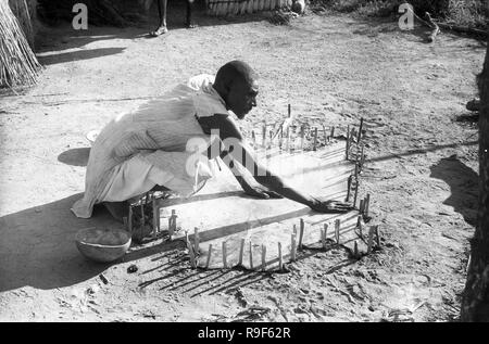 1950's Native People, West Africa tribesman drying animal skin in the sun Stock Photo