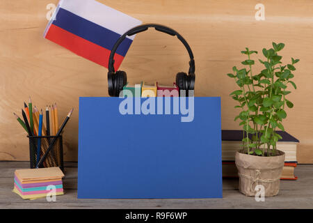 Concept of learning the russian language - blank paper, flag of the Russian Federation, books, headphones, pencils on wooden background Stock Photo