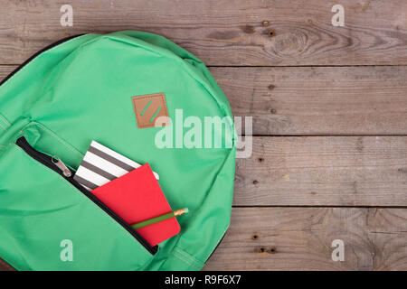 Backpack and school supplies: notepad, pencil on brown wooden table Stock Photo