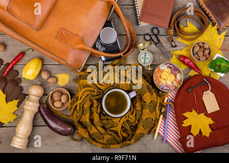 The concept of autumn travel - a cup of tea, vegetables, kitchen accessories, maple leaves, camera, compass, passport, scissors, key with blank label, Stock Photo