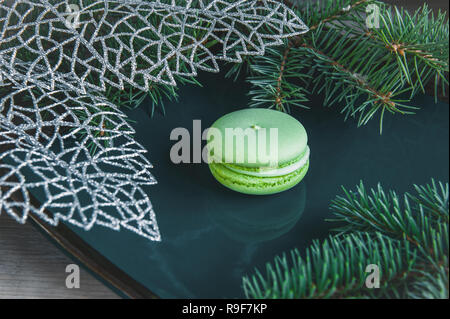 Fresh red macaroons at the Christmas table with the garland on the Christmas tree branches. Stock Photo