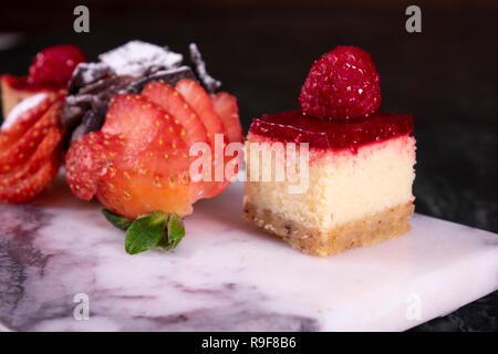 Set of mini cakes in assortment on white plate. Restaurant menu. Blackberry cake with raspberries. Tartlet with fruits. Close up. Stock Photo