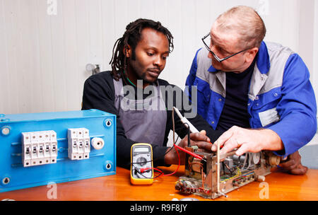 An experienced teacher teaching a young Electrician in the Workshop Stock Photo