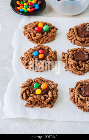 Chocolate bird's nest cookies with ganache and decorated with colorful candies on a white background. Stock Photo