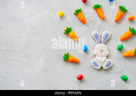 Easter bunny cookies and carrot chewing marmalade with candies on a white stone background. Top view and copy space. Stock Photo