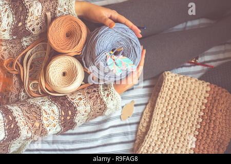 Woman holds three reel thread with blue knitting hook Stock Photo