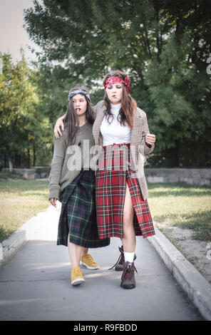 Two informally dressed girls walking down the street with cigarettes. Teenage problems. Stock Photo