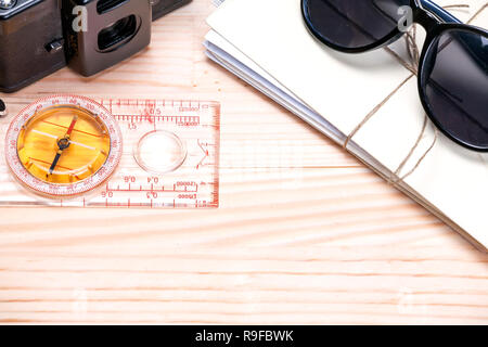 Sunglasses, bunch of letters, old film camera and a compass on a light wooden background with copy space on the bottom. Abstract of summer travels. Stock Photo
