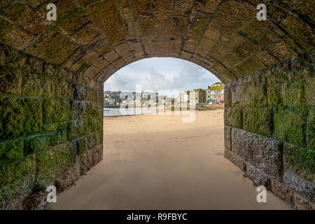 View through arch towards the quaint fishing harbour of St Ivres, on the North Cornwall coast. Stock Photo