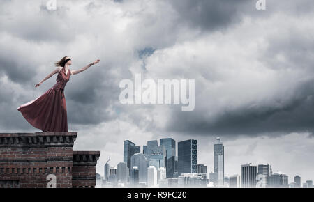 Blind woman in long red dress at top of building. Mixed media Stock Photo
