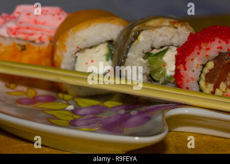 Sushi rolls with salmon, eel, cream cheese Philadelphia, caviar tobica and food sticks on the plate