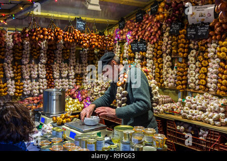 Frenchman / street vendor in booth selling garlic and French food specialities / regional products at Christmas market in winter Stock Photo