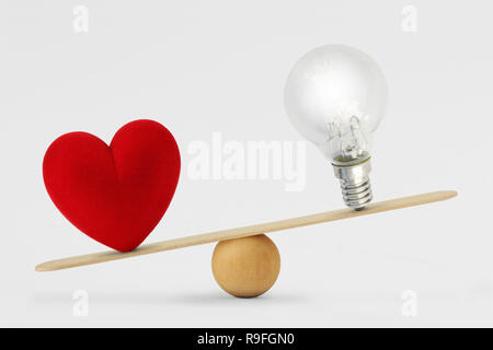 Heart and light bulb on scale - Concept of love priority over brain in life Stock Photo