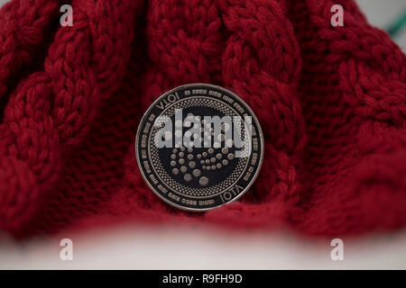 Iota cryptocurrency physical coin placed on red knitted Christmas hat Stock Photo