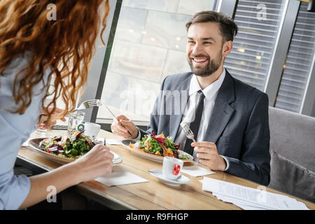Man and woman having business lunch at restaurant sitting at table eating healthy salad discussing work smiling joyful Stock Photo