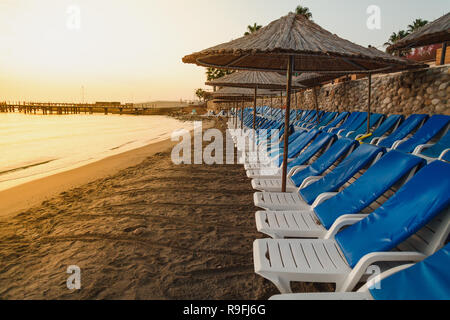 Empty sea beach in the early dawn morning. Sun beds and umbrellas are straight rows Stock Photo