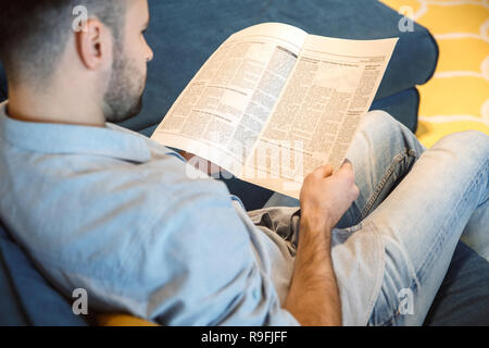 Bachelor middle-aged man daily routine in the living room reading newspaper back view Stock Photo