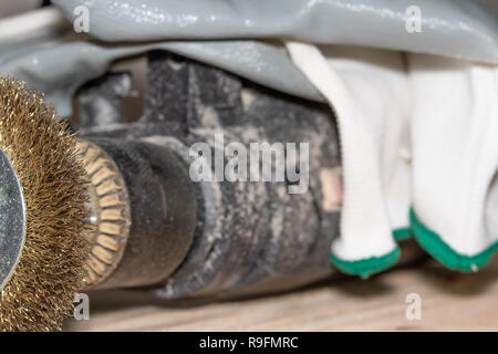 Good old carpentry, woodworking tools. Electric drill with a disc for processing wooden surfaces and gloves on a wooden joinery table after work has b Stock Photo
