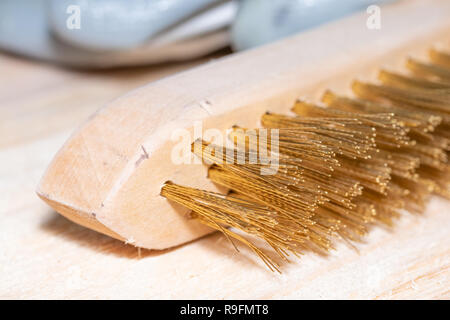 Good old carpentry tools for woodworking after work. Metal brush for treating wooden surfaces on a wooden joinery table. Stock Photo