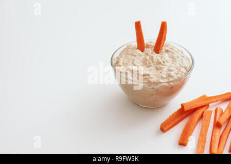 Quick snack. Hummus with carrot sticks. Cropped photo of humus with loaves of food balance isolated on white background. Stock Photo