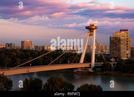 Bridge (Most SNP) linking both side of Bratislava at sunset, looking like UFO.  Communist block apartments of Petrzalka in background Stock Photo
