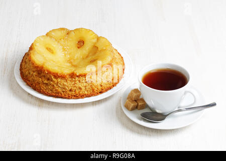 Pineapple Upside Down Cake and cup of tea on white wooden table Stock Photo
